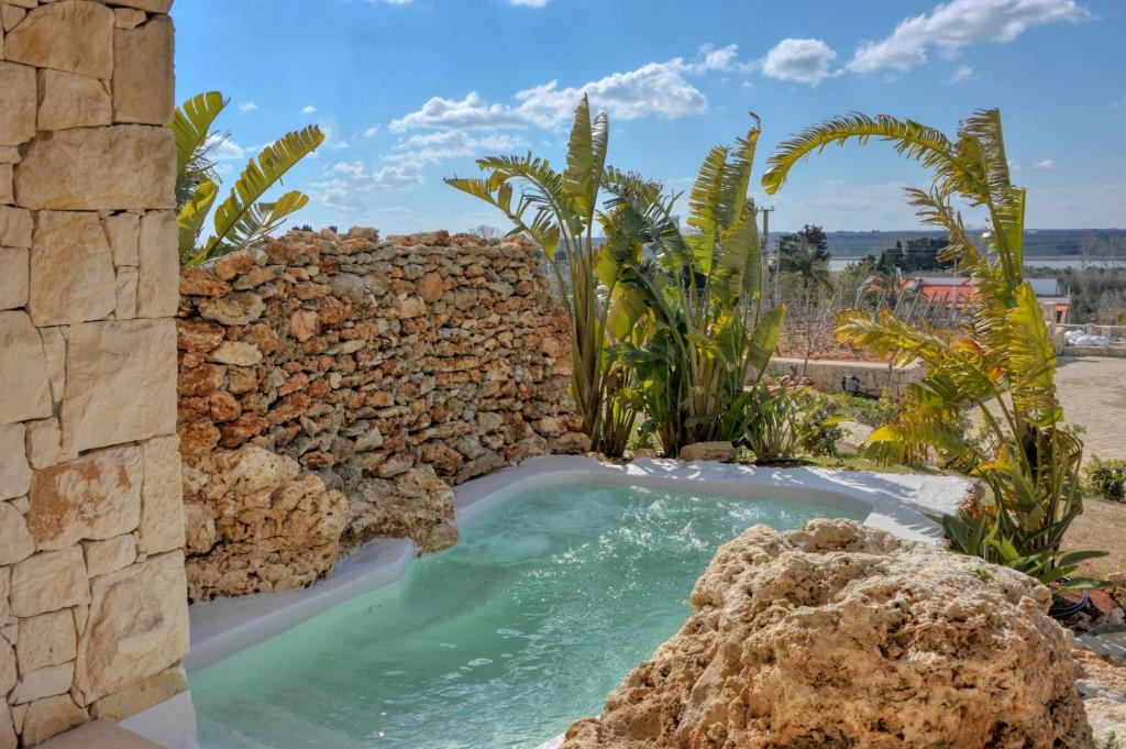 a swimming pool in a stone wall with a rock at Agriresort Murciano in Otranto