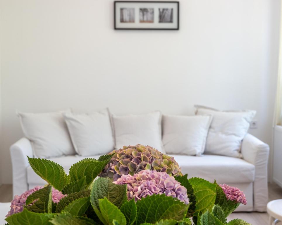 uma sala de estar com um sofá e um vaso de flores em Hortenzia Vendégház Mór em Mór