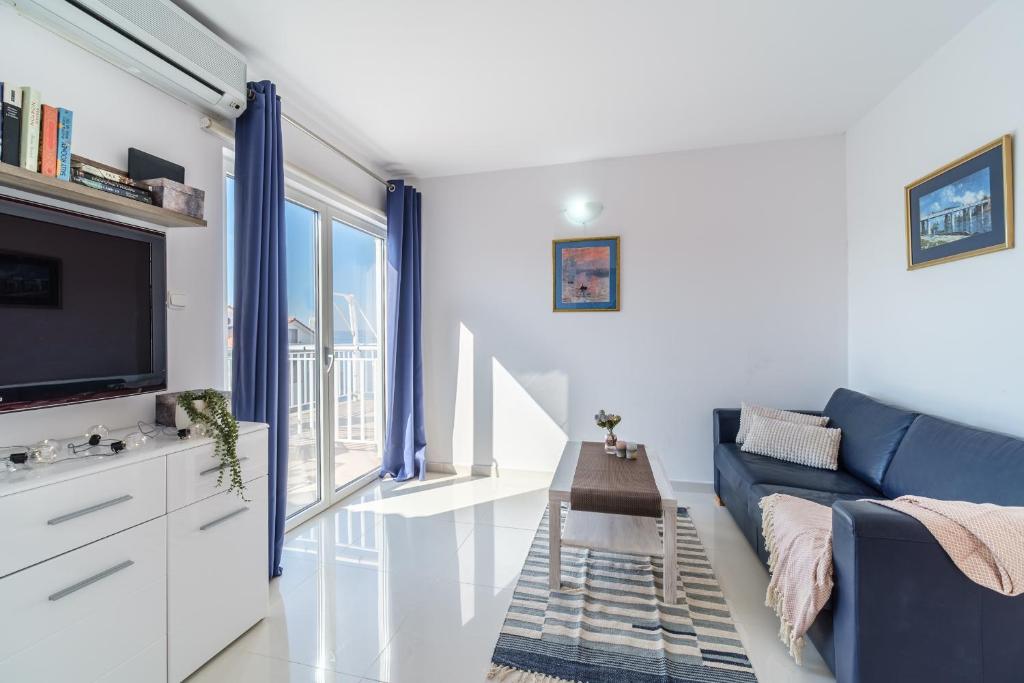 een woonkamer met een blauwe bank en een tv bij Luka's SEA View Terrace & Steps from the Beach apartment in Mirce