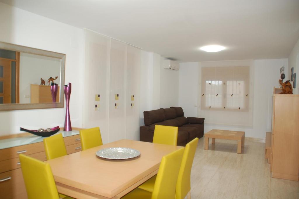a dining room and living room with a table and yellow chairs at PROALMAR, chalet 17 in Peñíscola