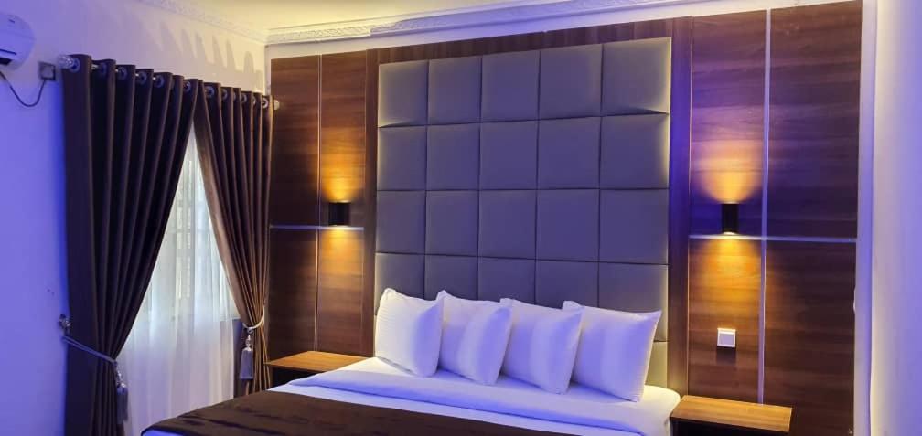 a bedroom with a large bed with a large headboard at Presken Hotel at International Airport Road in Ikeja