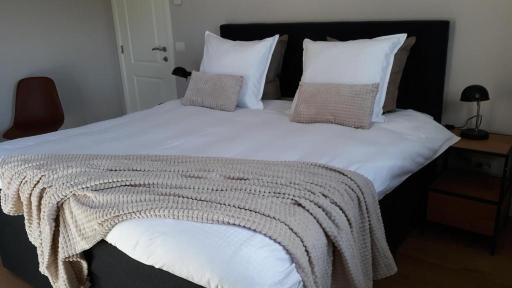 1 cama grande con sábanas y almohadas blancas en B&B Valant, en Brujas