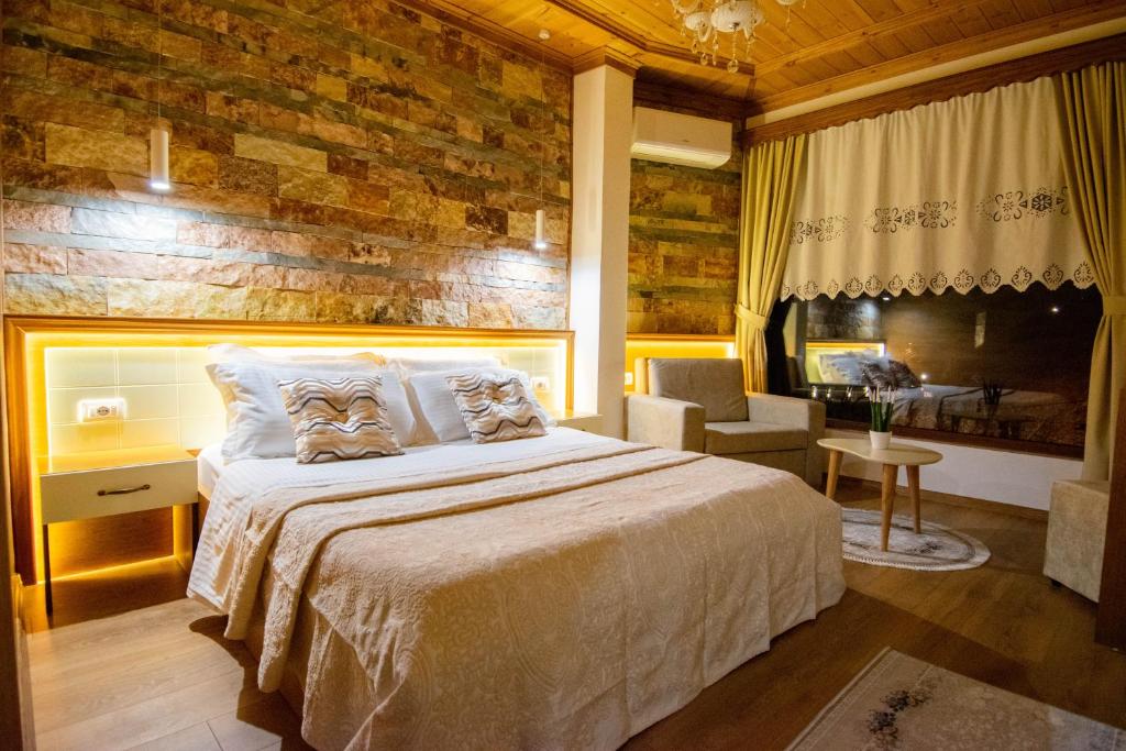um quarto com uma cama grande e uma parede de tijolos em Te Kalaja Rooms em Gjirokastër