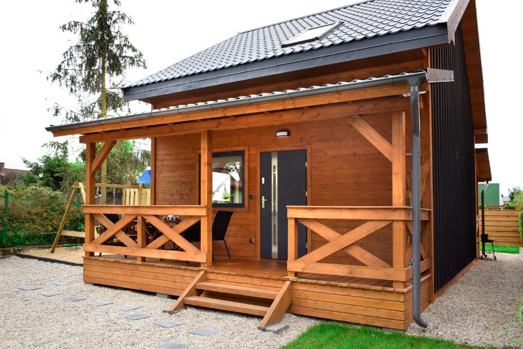 a wooden shed with a door and a porch at Nadmorskie Klimaty - Domki Całoroczne in Stegna