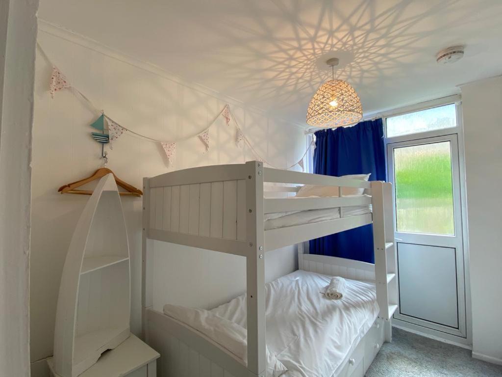 Ce lit superposé blanc se trouve dans un dortoir doté d'un plafond. dans l'établissement 3 Bedroom Cottage minutes walk from town, harbour & Beaches., à St Ives