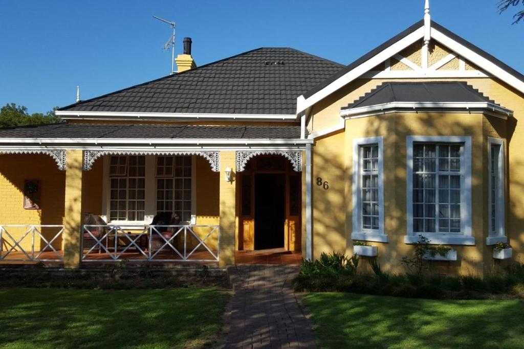 a yellow house with a front door and a porch at Lali's Guest House in Harrismith