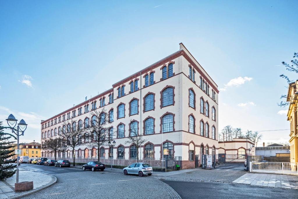 um grande edifício branco com carros estacionados em frente em Loft im Denkmal em Heidenau