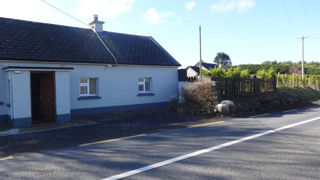 uma casa branca na berma de uma estrada em Sligo Wild Atlantic Cottage em Sligo