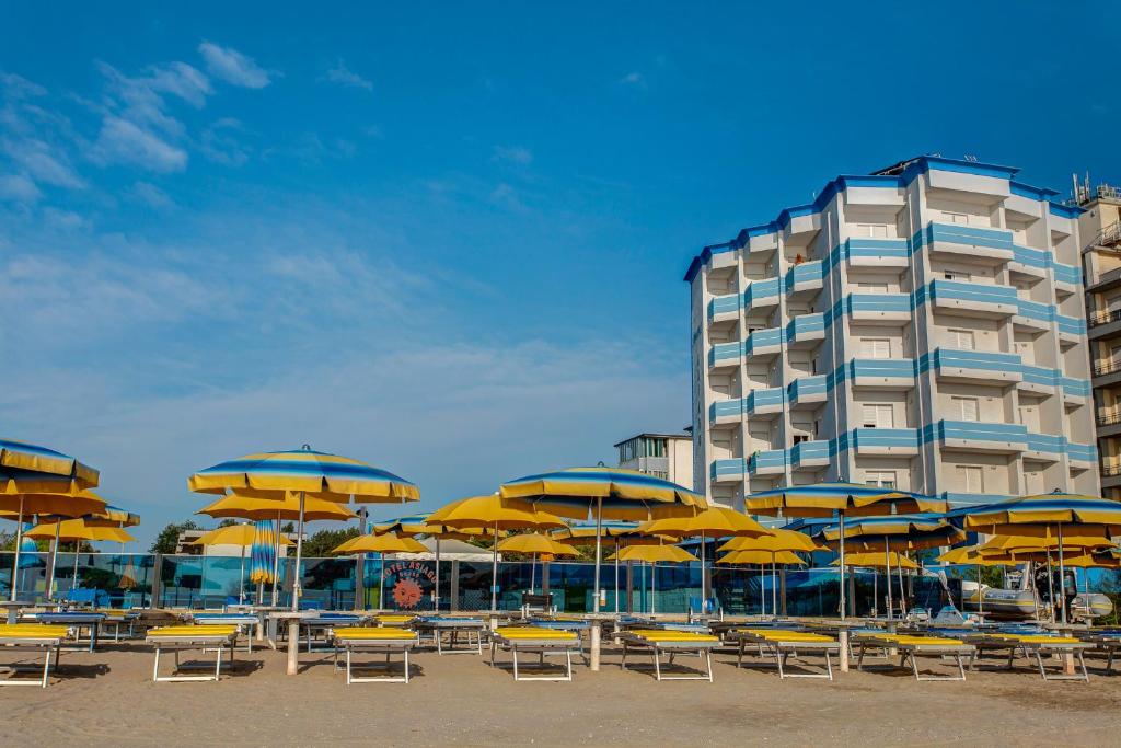 a beach with chairs and umbrellas and a building at Hotel Asiago Beach in Lido di Savio
