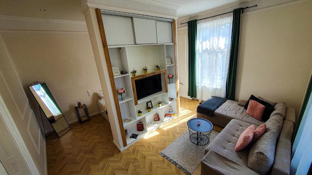 salon z kanapą i telewizorem w obiekcie SMARAGD Apartman w Győr