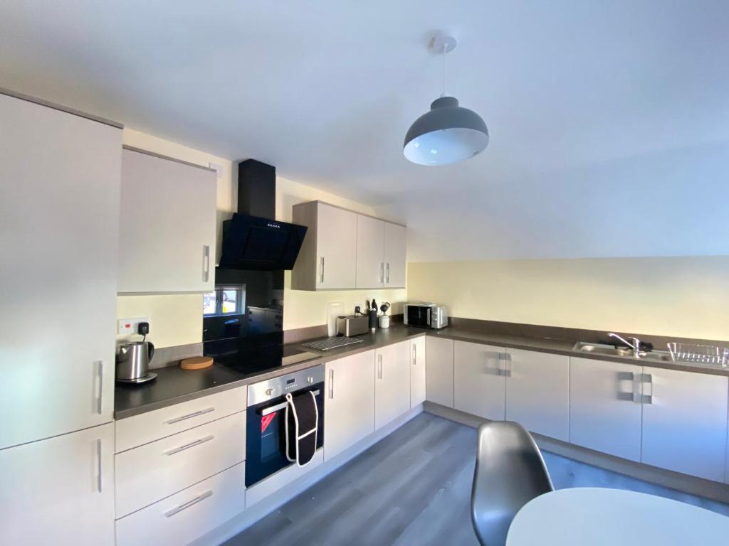 una cocina con armarios blancos y encimeras negras en Hodge Bower Holidays, Ironbridge - Sedgwick, en Ironbridge