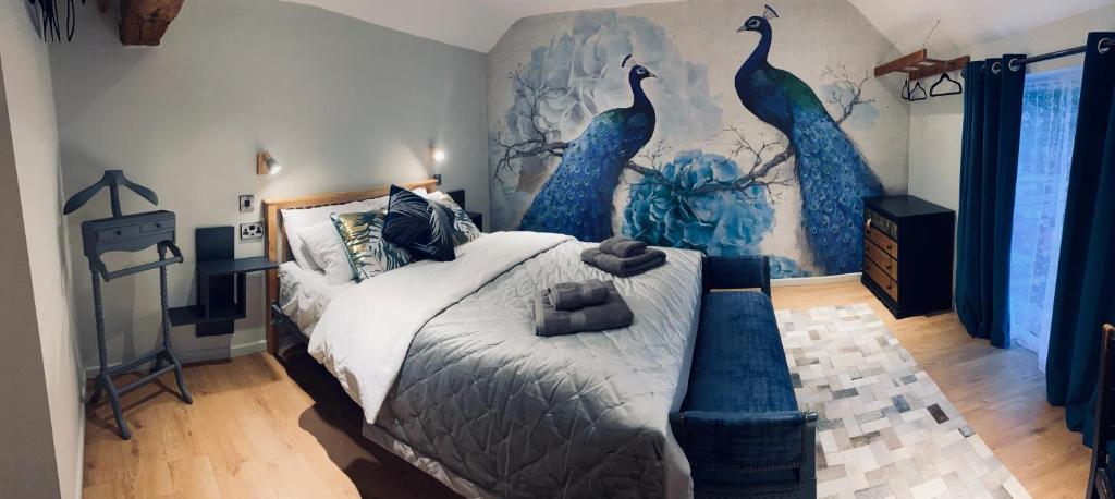 una camera da letto con un grande letto dipinto a parete con pavoni blu di Inn The Moors a Cresswell