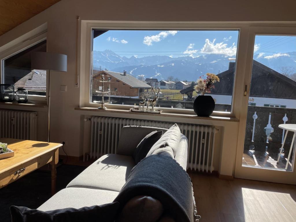 a person laying on a couch looking out of a window at Alpenblick in Farchant
