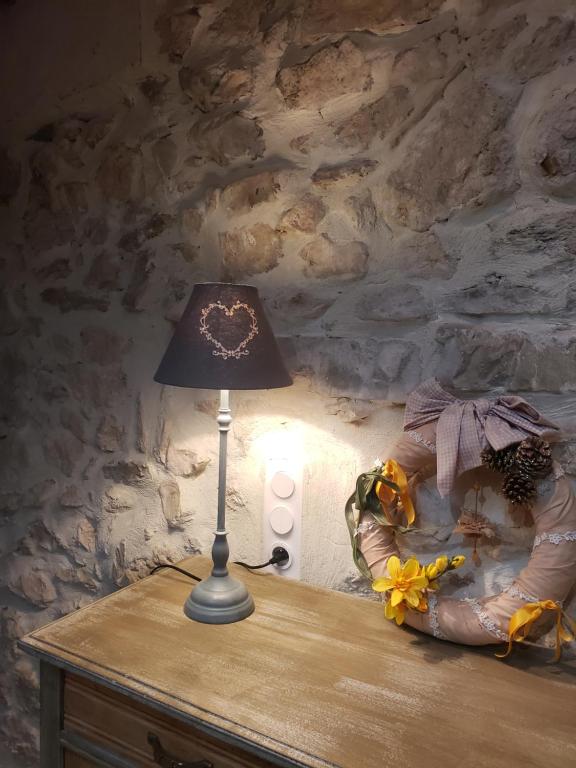 una lámpara sentada en una mesa junto a una pared de piedra en Le Chateau, en Camps-sur-lʼAgly