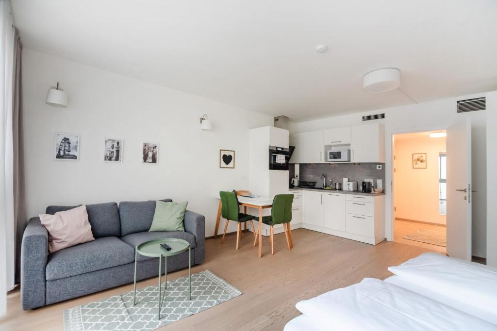 a living room with a couch and a table and a kitchen at Quiet and cozy apartment next to Mariahilfer Strasse and Naschmarkt with AC in Vienna