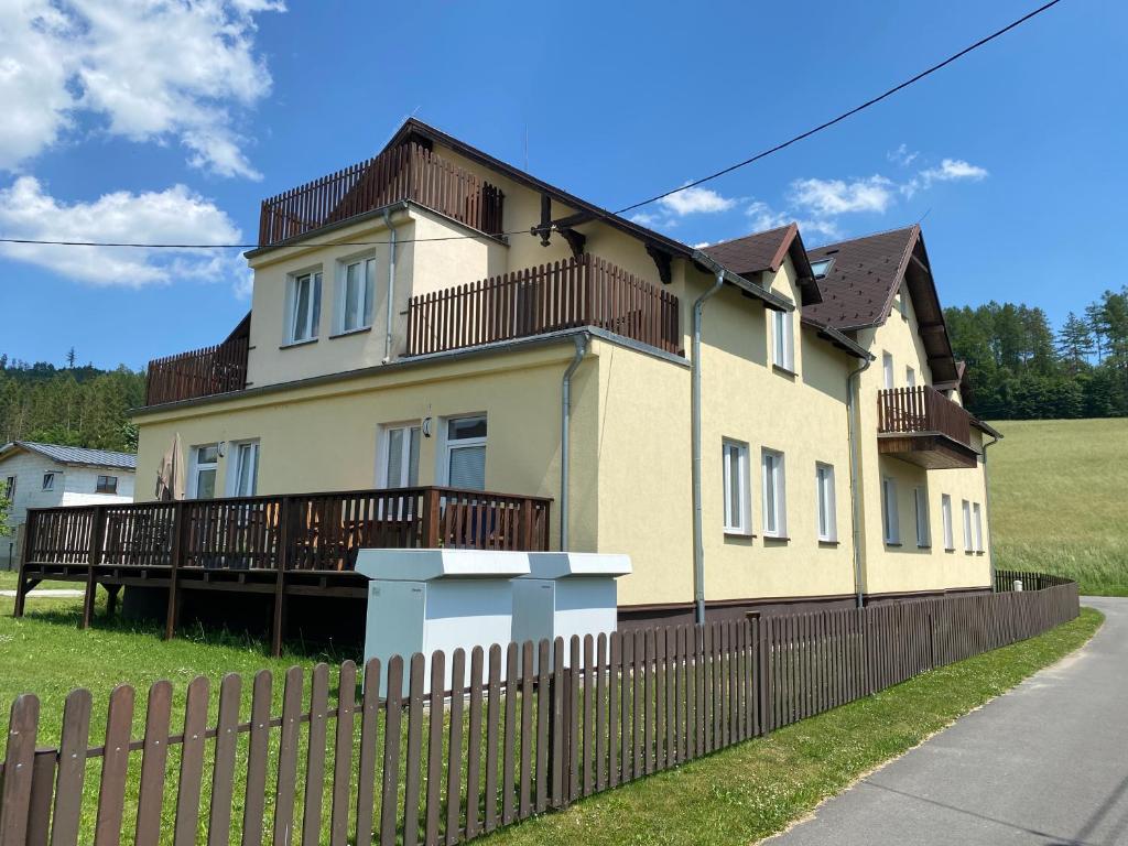 a large yellow house with a wooden fence at Karlovický dvůr 251 in Karlovice