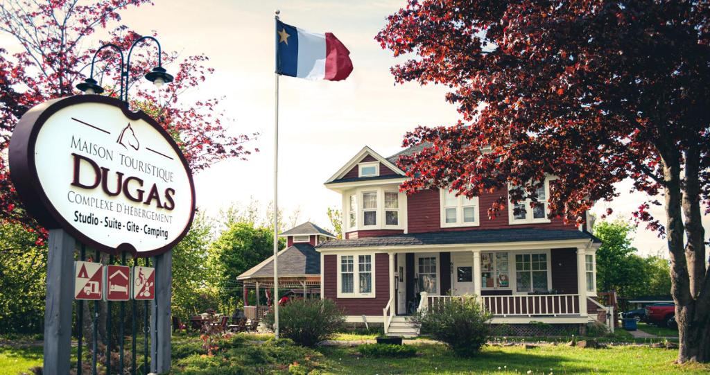 un panneau devant une maison arborant un drapeau dans l'établissement Complexe d'hébergement la Maison touristique Dugas, à Caraquet