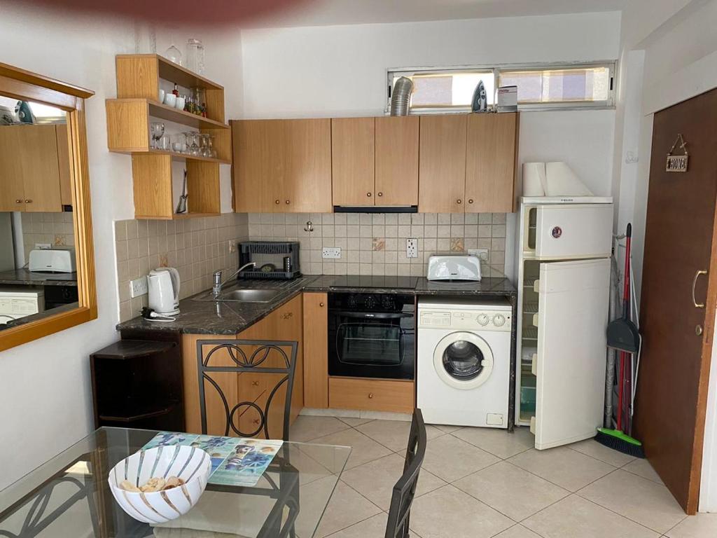 een keuken met houten kasten en een wit apparaat bij 1 bedroom flat 200m from the beach in germasogia tourist area in Limassol