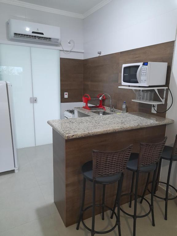 een keuken met een aanrecht met vier barkrukken bij Moriá Flats in Ubatuba