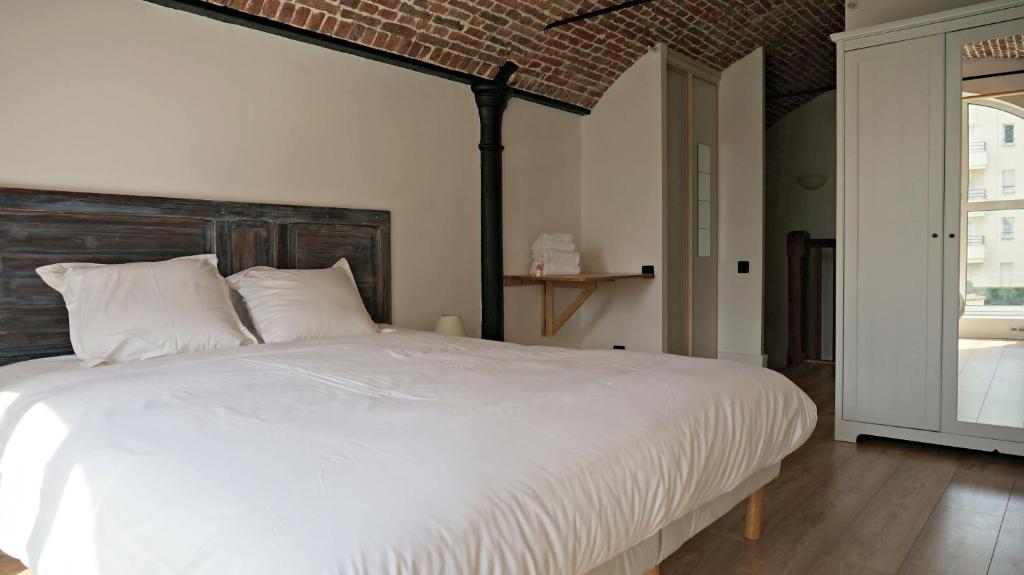 um quarto com uma grande cama branca e uma parede de tijolos em Little Suite - Coline em Lille