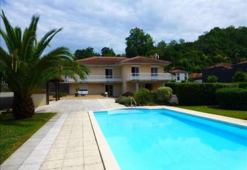 a large swimming pool in front of a house at Les Caraïbes in Peyrehorade