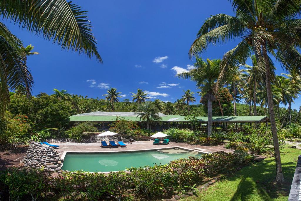a swimming pool with chairs and palm trees at Maravu Taveuni Lodge in Matei