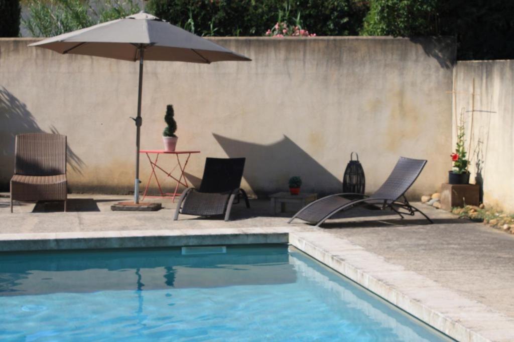 uma piscina com duas cadeiras e um guarda-sol em Les Mazets de Pascale em Saint-Rémy-de-Provence