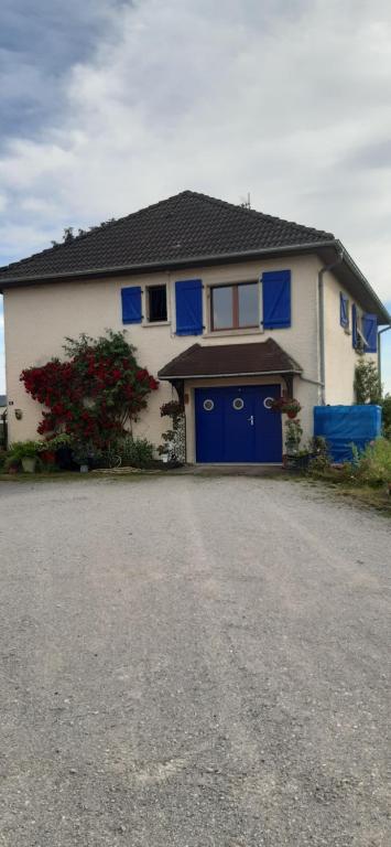 une maison blanche et bleue avec un garage bleu dans l'établissement Guiguitte, à La Chapelle-lès-Luxeuil