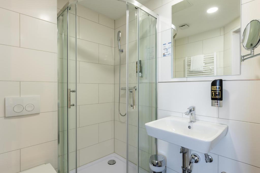 ein Bad mit einer Glasdusche und einem Waschbecken in der Unterkunft Trip Inn Hotel Münster City in Münster