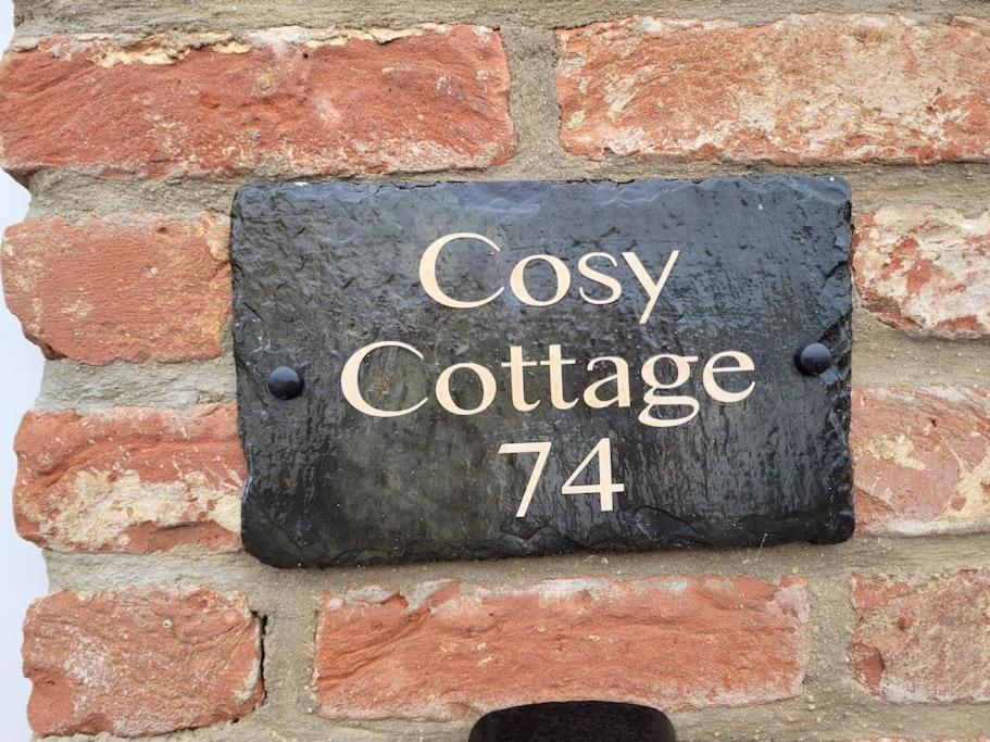 um sinal numa parede de tijolos que lê chalé acolhedor em Cosy Cottage,The Paddock BARMSTON. NR BRIDLINGTON em Great Driffield