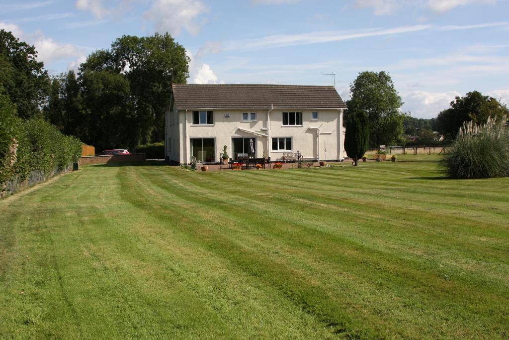 a white house with a large grass field at Broadwell Guest House in Meriden