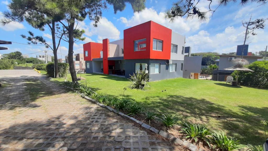 a house with a red roof on a green yard at ELEMENTOS MAR AZUL a 30 mts de la playa in Mar Azul