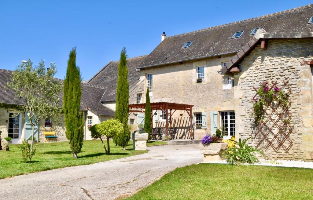 una gran casa de piedra con una puerta en un patio en L'Ecurie Gourmande, en Thaon