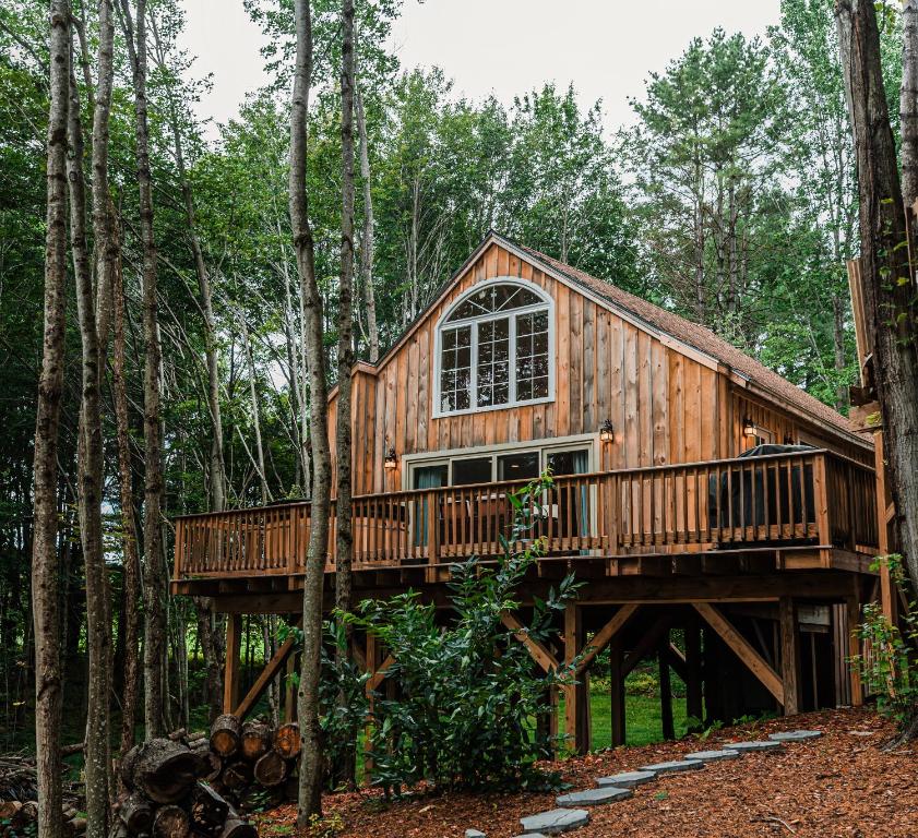 una casa del árbol en el bosque con un hombre de pie en la cubierta en MoonLight Treehouse At Belgrade Hospitality en Belgrade