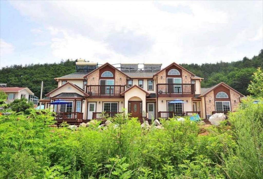 a large house with a mountain in the background at Prime Pension in Yangyang