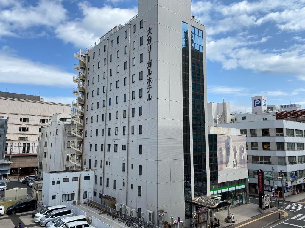 ein hohes weißes Gebäude mit Autos in einer Stadt in der Unterkunft Oita Regal Hotel in Ōita