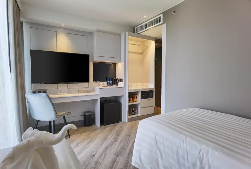 A guest room with a large bed, television wall, desk, and open wardrobe.