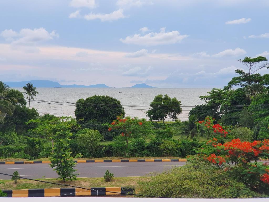 a road with a view of the ocean and trees at Visal Sak Guesthouse in Kep