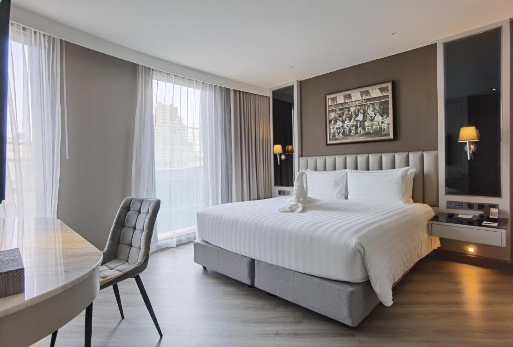 A larger-looking bedroom includes a dining-style table, upholstered chair and bright floor-to-ceiling windows.