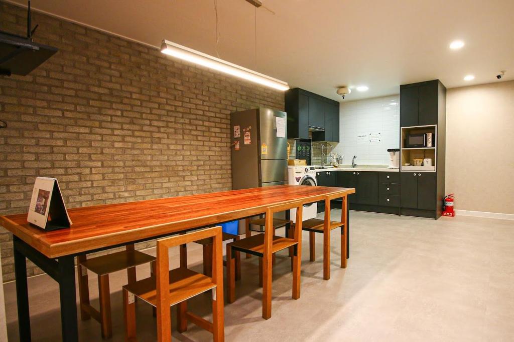 una cucina con un lungo tavolo in legno e sedie di Lighthouse Guesthouse a Mokpo