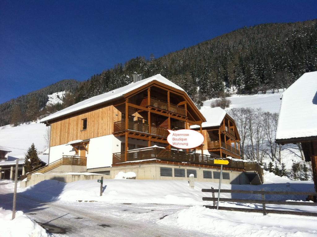 un gran edificio de madera en la nieve con una montaña en Alpenrose Boutique by Globalimmoservice, en Bad Kleinkirchheim