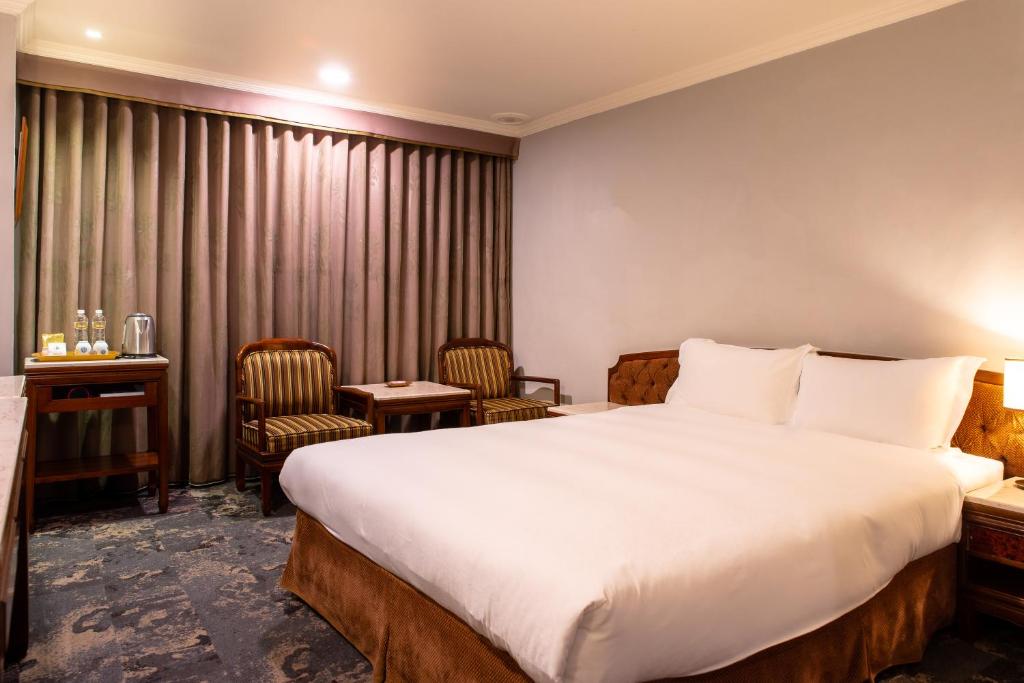 a hotel room with a bed and a table and chairs at Chiayi King Hotel in Chiayi City