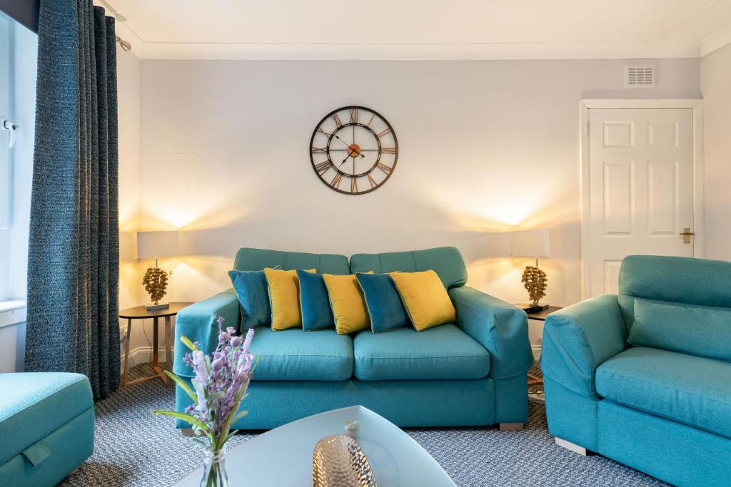a living room with a blue couch and a clock on the wall at Two Bedroom Ground Floor Flat in Bridge of Allan