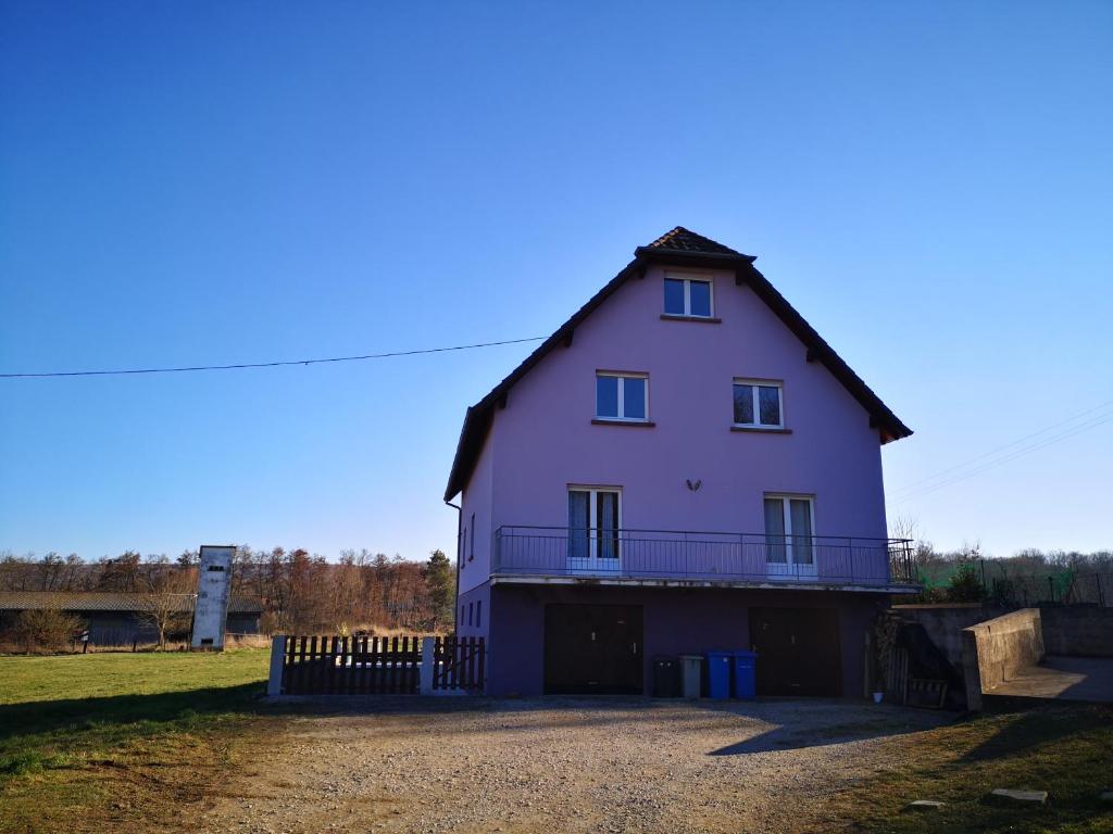 ein großes lila Haus mit einem Zaun auf einem Feld in der Unterkunft A l'orée du bois in Romanswiller