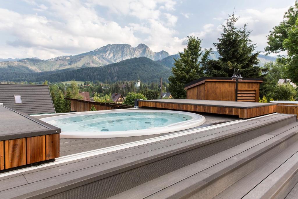 a hot tub on a deck with mountains in the background at Tatra Resort & SPA in Kościelisko