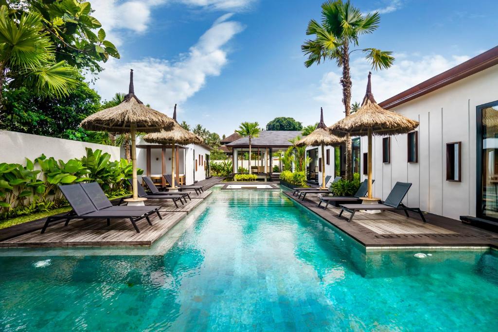 a pool at a villa with chairs and umbrellas at Villa Lagoon by BaliSuperHost in Ubud