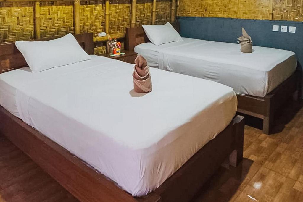 two beds with shoes sitting on them in a room at Villa Bambu Rinjani & Restaurant Mitra RedDoorz in Senaru