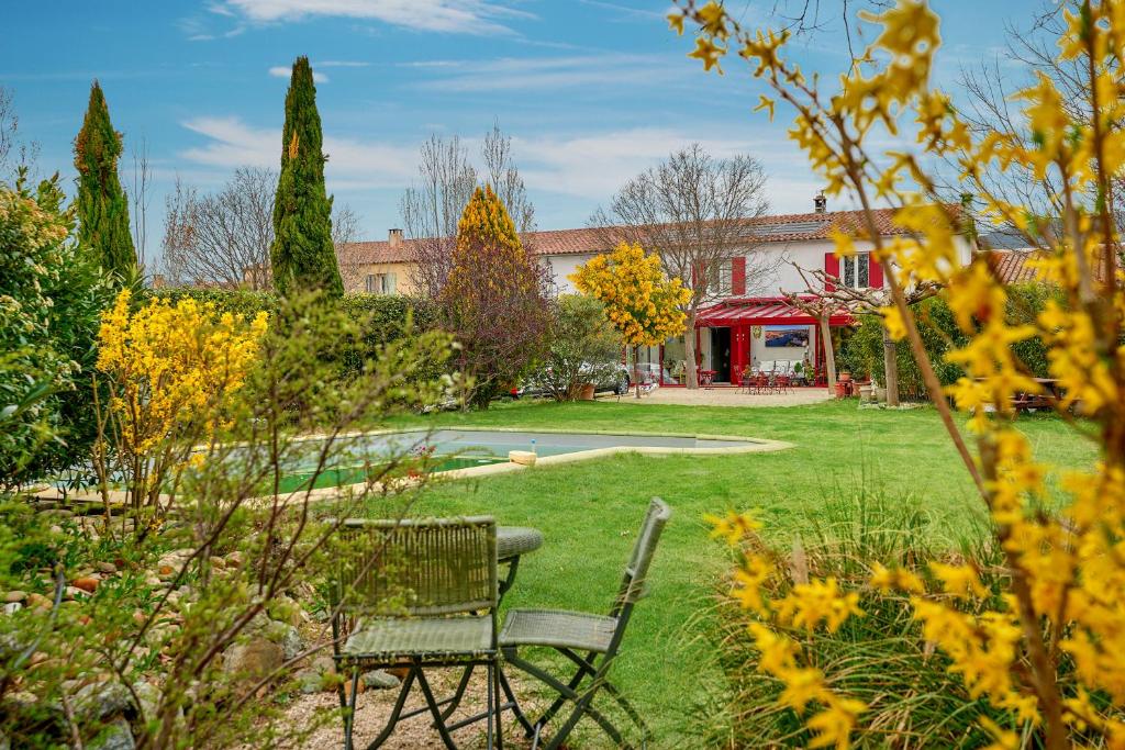 un jardín con mesa y sillas en el patio en Clos des hérissons, chambre mimosa, piscine, jardin, en Lauris