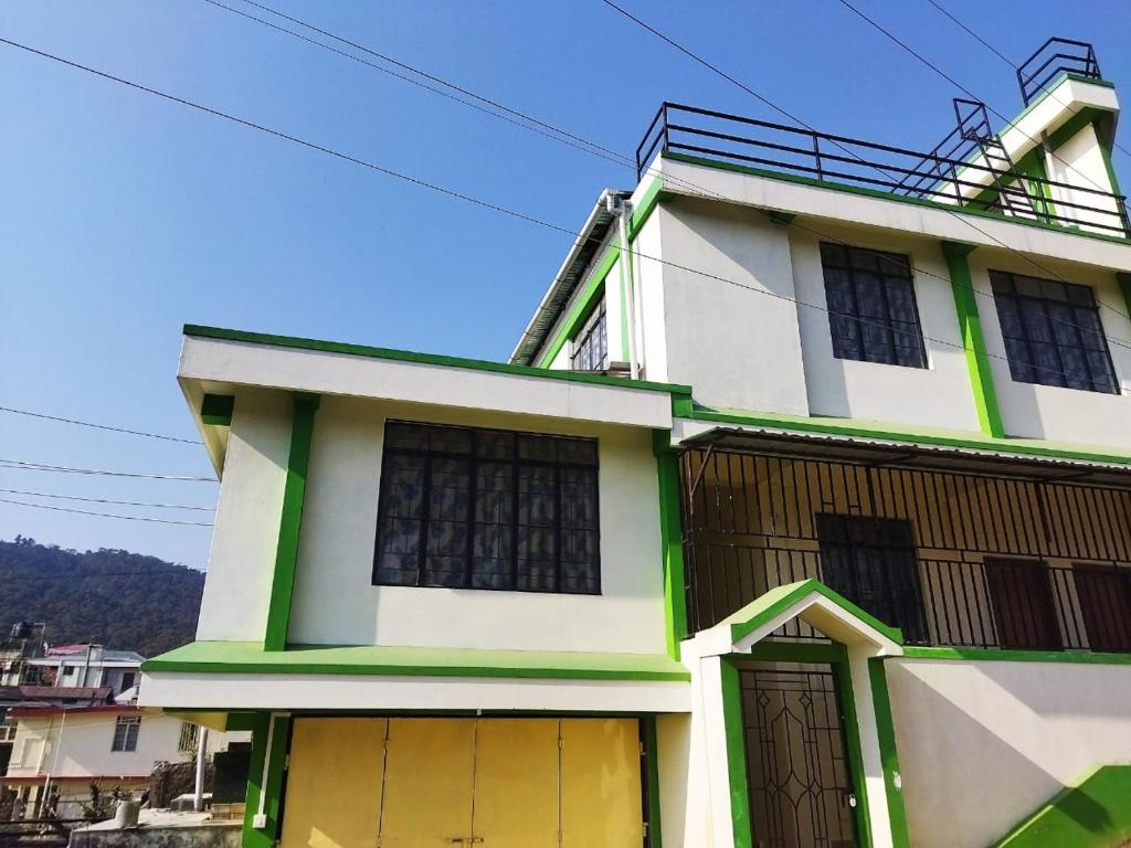 a white and green house with yellow doors at HEEMSTEDE in Shillong