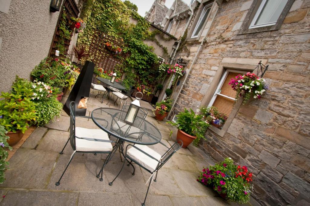 een patio met een tafel, stoelen en bloemen bij Rosehill Guest House in Pitlochry